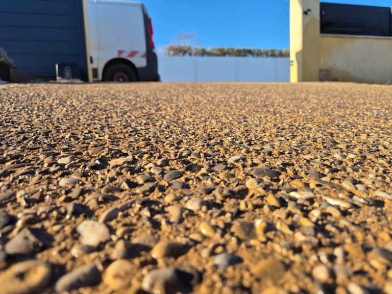 Béton désactivé aux galets apparents dans une cour, réalisé par Gonsalves Paysages