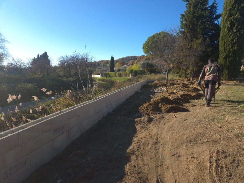 Maçon de Gonsalves Paysages montant un mur en agglo dans un jardin près de Manosque