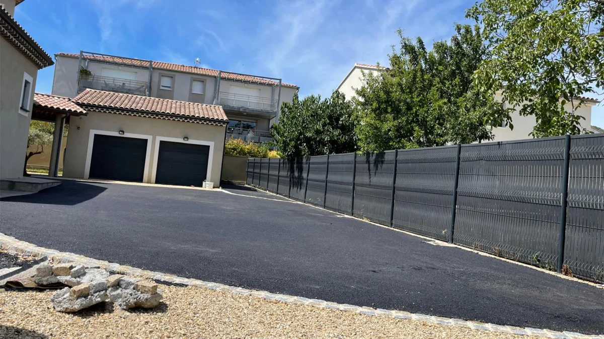 Cour en enrobé bitumineux devant deux garages, réalisée par Gonsalves Paysages
