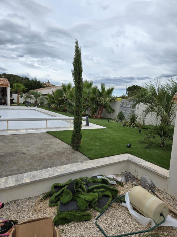 Jardin exotique avec palmiers et gazon synthétique en cours de pose par Gonsalves Paysages