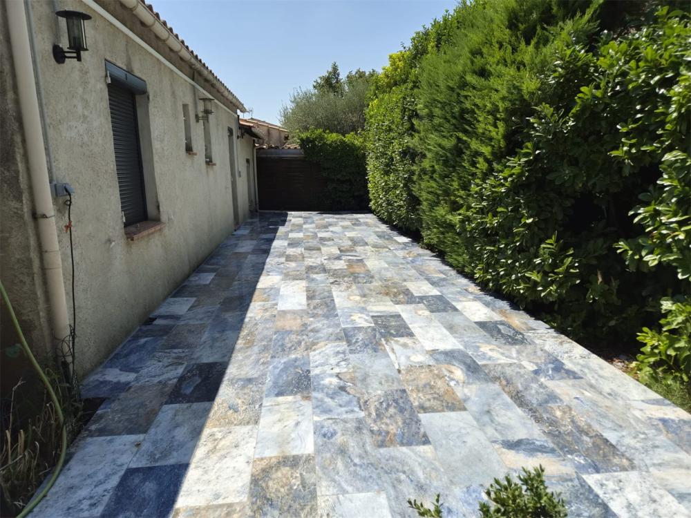 Terrasse carrelée en dalles de pierre bleue le long d'une maison, réalisée par Gonsalves Paysages